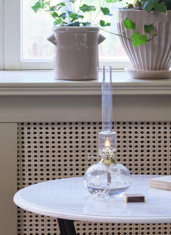 Tänd vit fotogenlampa på marmorbord framför fönster med blomkrukor